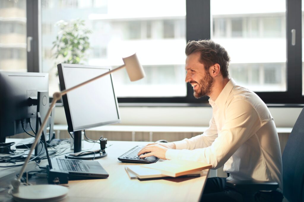 A man in a white shirt is using a laptop to see the safeguarding services offered by Checks Direct.